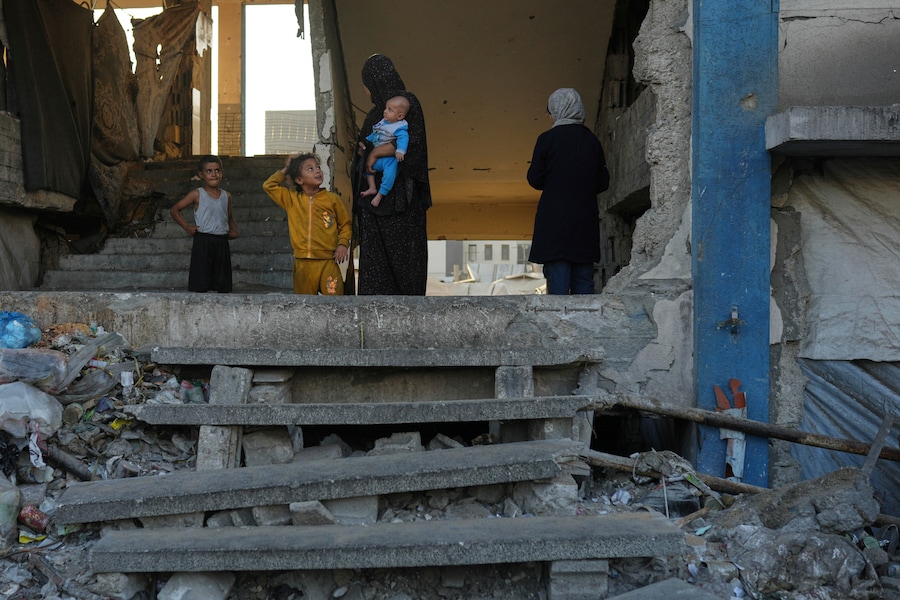 Una donna palestinese sfollata tiene in braccio il suo bambino mentre parla con dei bambini in una scuola usata come rifugio a Gaza City, mercoledì 27 agosto 2025. (Foto AP/Jehad Alshrafi) (APN)