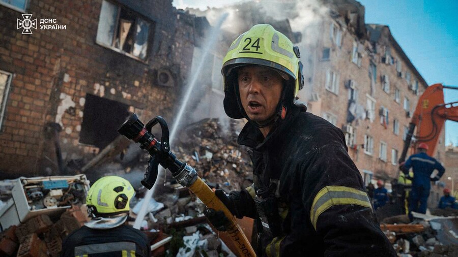 I vigili del fuoco che spengono un incendio in un edificio residenziale pesantemente danneggiato durante un attacco di droni e missili russi su larga scala a Kiev. (AFP)