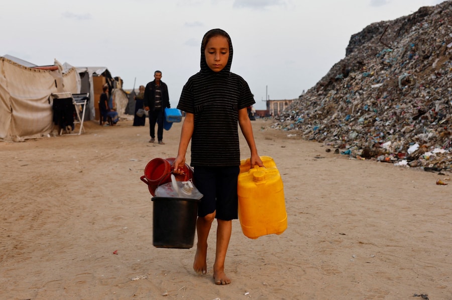 Una ragazza palestinese sfollata cammina per raccogliere acqua. (REUTERS)