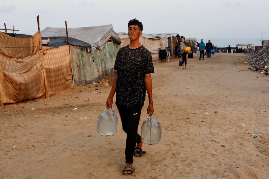 Un ragazzo palestinese sfollato raccoglie acqua. (REUTERS)