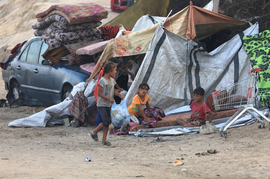 Palestinesi sfollati siedono accanto a una tenda. (REUTERS)