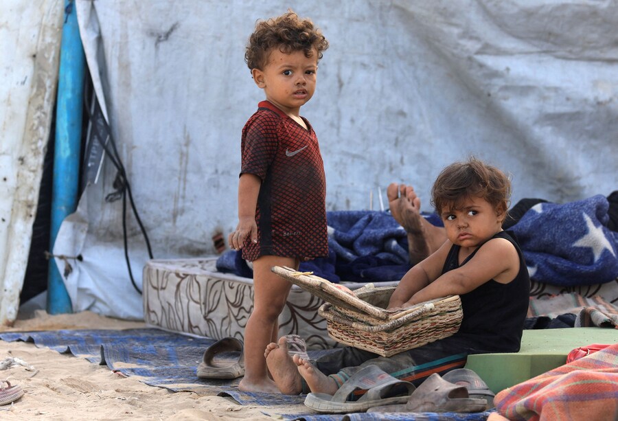 Bambini palestinesi sfollati si riparano sul ciglio di una strada. (REUTERS)