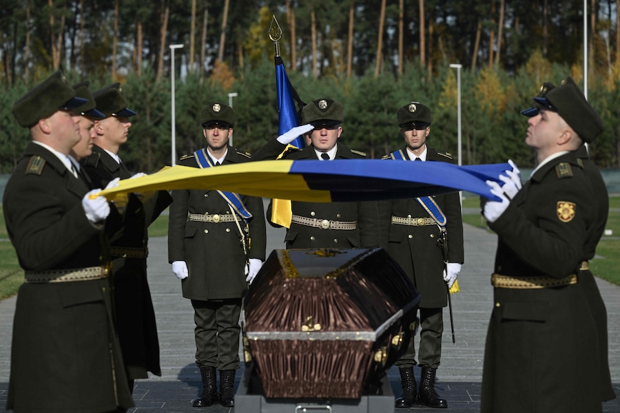 I militari della Guardia d’Onore tengono una bandiera ucraina sopra la bara di un soldato ucraino non identificato durante la cerimonia funebre presso il Cimitero Nazionale Militare Memoriale vicino a Kiev (AFP)