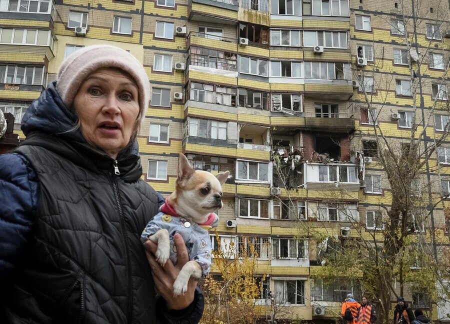 Una donna con un cane cammina vicino a un condominio colpito durante l’attacco di un drone russo a Dnipro (REUTERS)