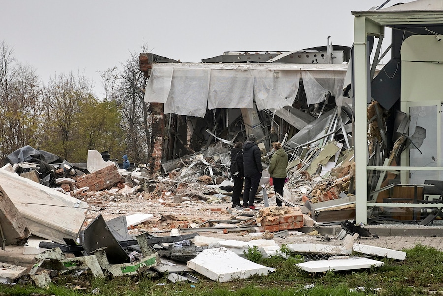 La gente del posto osserva una stazione di servizio distrutta sul luogo dei bombardamenti russi a Kharkiv, nell’Ucraina nord-orientale (EPA)