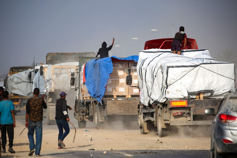 Palestinesi sfollati assaltano camion che percorrono la strada di Salah al-Din, nella Striscia di Gaza centrale, vicino a Deir al-Balah, nel tentativo di ottenere aiuti umanitari, il 9 novembre 2025. (Foto di Eyad Baba / AFP) (AFP)
