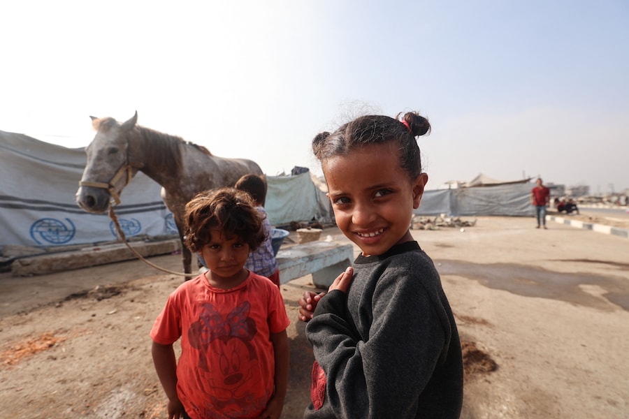 Due bambini si trovano vicino a un cavallo nel campo profughi di Nuseirat, nella Striscia di Gaza centrale, il 9 novembre 2025, dopo la tregua siglata dagli Stati Uniti che ha fermato la guerra di due anni. La prima fase dell'accordo per il cessate il fuoco a Gaza, mediato il mese scorso dal Presidente degli Stati Uniti, ha aperto la strada allo scambio di ostaggi israeliani e prigionieri palestinesi. (Foto di Eyad Baba / AFP) (AFP)