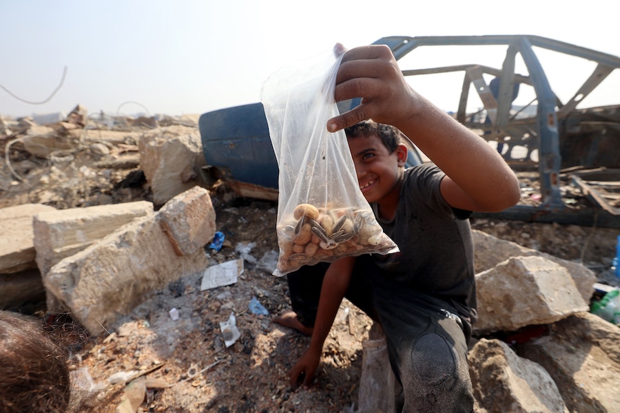 Un ragazzo palestinese mostra un sacchetto di semi e noci che ha raccolto dalla sabbia lungo il ciglio di una strada vicino al campo profughi di Nuseirat, nella Striscia di Gaza centrale, il 9 novembre 2025, dopo la tregua promossa dagli Stati Uniti che ha fermato la guerra di due anni. La prima fase dell'accordo per il cessate il fuoco a Gaza, mediato il mese scorso dal presidente degli Stati Uniti, ha aperto la strada allo scambio di ostaggi israeliani e prigionieri palestinesi. (Foto di Eyad Baba / AFP) (AFP)