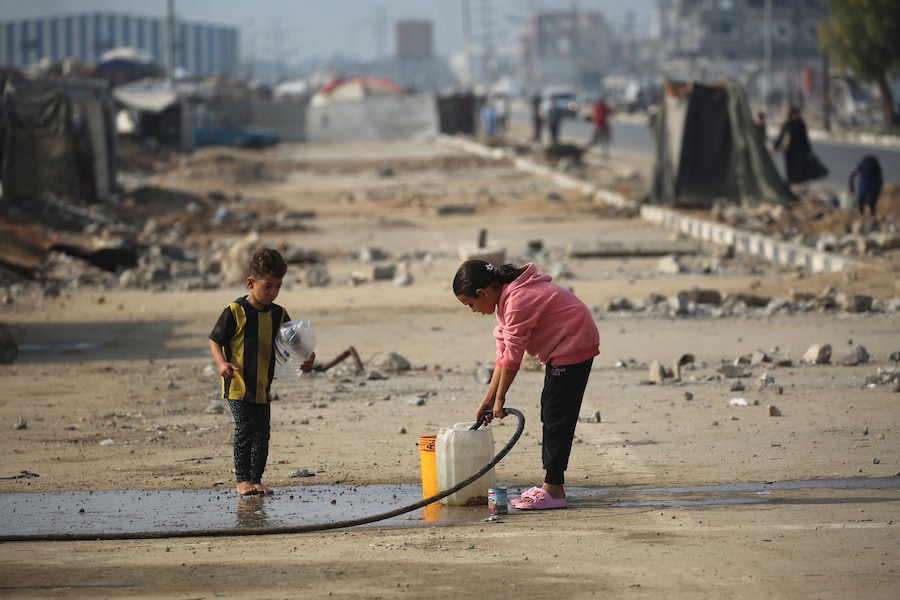 Bambini palestinesi riempiono un contenitore d'acqua lungo una strada vicino al campo profughi di Nuseirat, nella Striscia di Gaza centrale, il 9 novembre 2025, in seguito alla tregua promossa dagli Stati Uniti che ha fermato la guerra di due anni. La prima fase dell'accordo per il cessate il fuoco a Gaza, mediato il mese scorso dal Presidente degli Stati Uniti, ha aperto la strada allo scambio di ostaggi israeliani e prigionieri palestinesi. (Foto di Eyad Baba / AFP) (AFP)