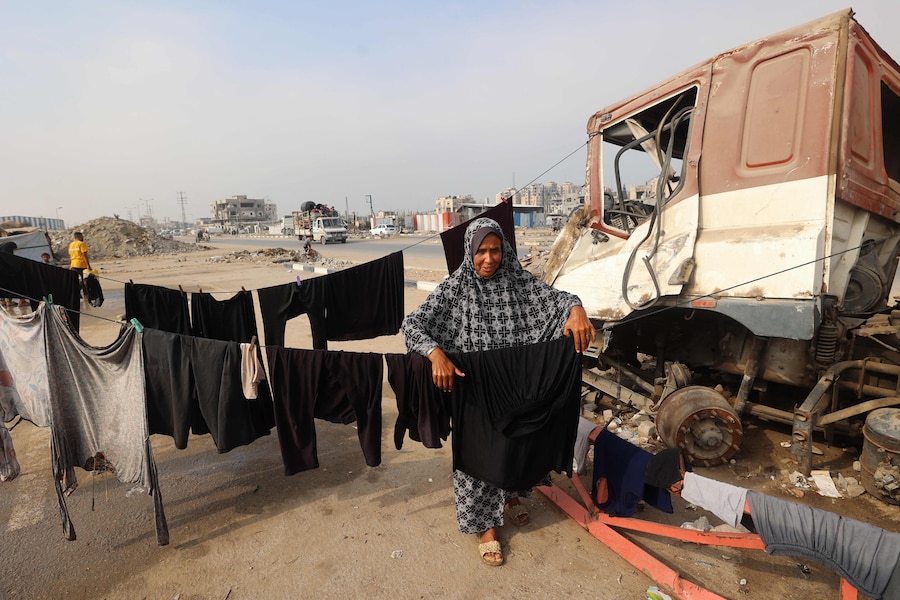 Una donna palestinese stende il bucato su un filo attaccato a un camion distrutto vicino al suo rifugio, lungo una strada vicino al campo profughi di Nuseirat, nella Striscia di Gaza centrale, il 9 novembre 2025, dopo la tregua promossa dagli Stati Uniti che ha fermato la guerra di due anni. La prima fase dell'accordo per il cessate il fuoco a Gaza, mediato il mese scorso dal Presidente degli Stati Uniti, ha aperto la strada allo scambio di ostaggi israeliani e prigionieri palestinesi. (Foto di Eyad Baba / AFP) (AFP)