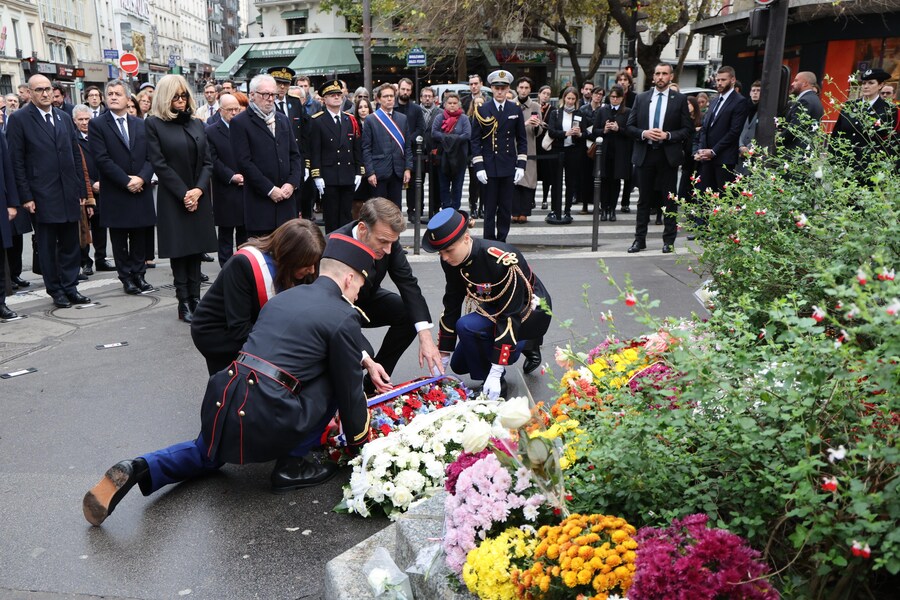 Il presidente francese Emmanuel Macron (al centro) e il sindaco di Parigi Anne Hidalgo (al centro-sinistra) depongono una corona di fiori a un incrocio vicino al Café Bonne Biere, uno dei luoghi presi di mira negli attacchi di Parigi del novembre 2015 (EPA)