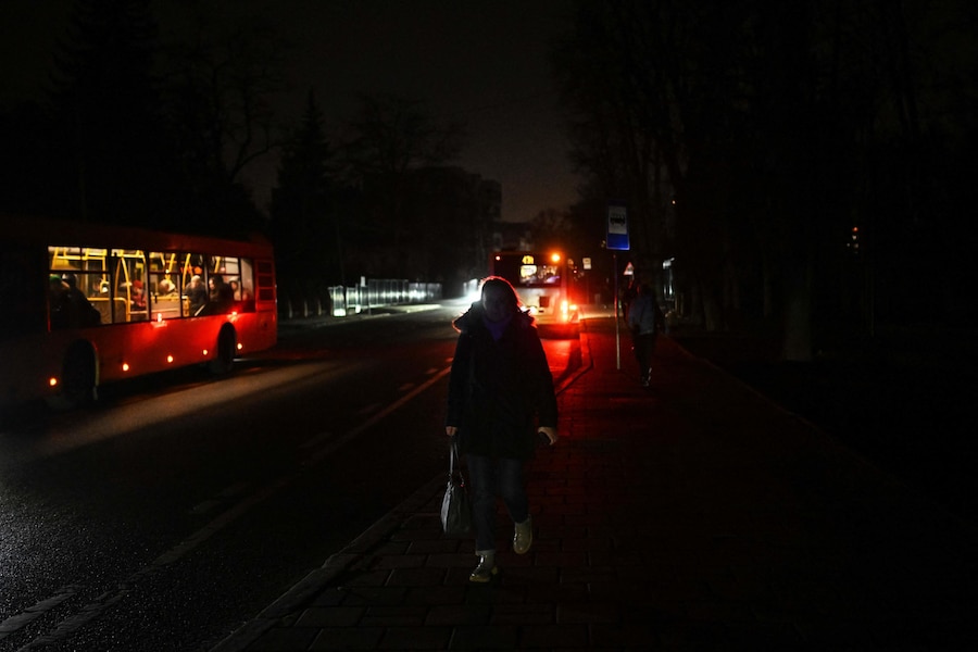 Una donna cammina lungo una strada non illuminata durante un'interruzione di corrente a Lviv. (Foto di Sergei Gapon / AFP)