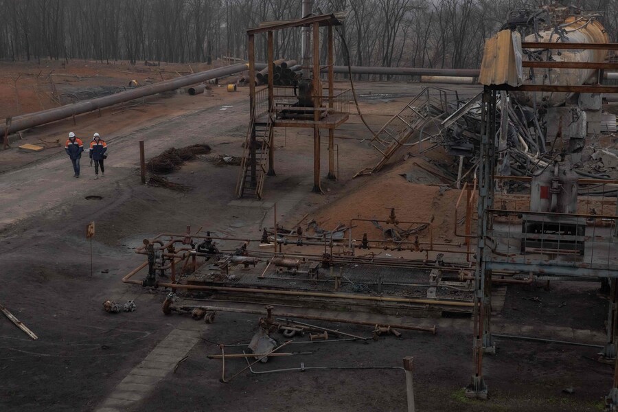 Dipendenti passano davanti a parti danneggiate dell'impianto di gas Naftogaz, a seguito di attacchi missilistici e di droni russi, in Ucraina. (Roman Pilipey / AFP)