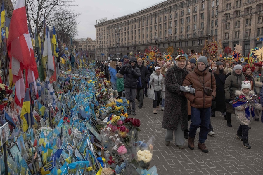 Ucraini in abiti tradizionali passano davanti al monumento ai caduti ucraini e stranieri in Piazza Indipendenza mentre partecipano a una processione natalizia nel centro di Kiev il 25 dicembre 2025, durante l'invasione russa dell'Ucraina. (Foto di Roman PILIPEY / AFP) (AFP)