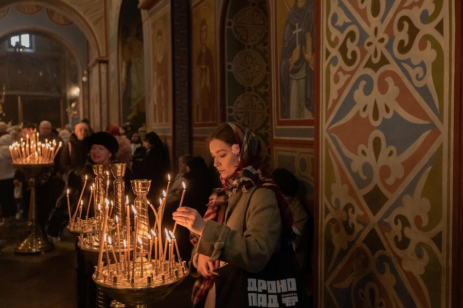 Una donna accende una candela durante l'allarme di un attacco aereo nel giorno di Natale al Monastero di San Michele dalla cupola d'oro, a Kiev, il 25 dicembre 2025, durante l'invasione russa dell'Ucraina. (Foto di Roman PILIPEY / AFP) (AFP)