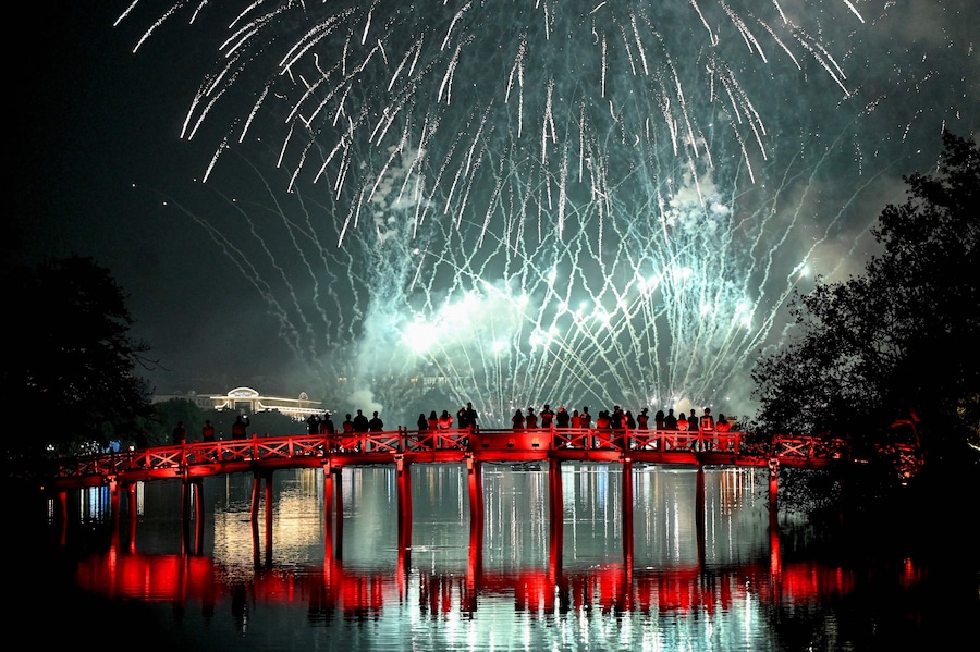 Alcune persone guardano i fuochi d'artificio di Capodanno dal ponte Huc sul lago Hoan Kiem ad Hanoi il 1° gennaio 2026. (Nhac Nguyen / AFP)