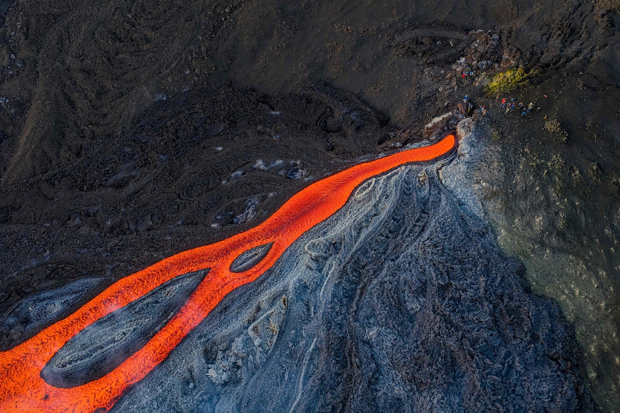 Questa veduta aerea mostra delle persone in piedi vicino a una colata di lava proveniente dal vulcano Etna (Torre del Filosofo - Etna Sud). (Giuseppe Distefano / AFP)
