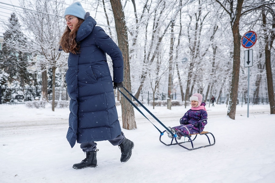 Yuliia Chumak, 32 anni, incinta di otto mesi, trascina la figlia Kvitoslava di 3 anni su una slitta mentre passeggiano nel loro quartiere durante un’interruzione di corrente. Kiev, Ucraina, 14 gennaio 2026. REUTERS/Alina Smutko (REUTERS)