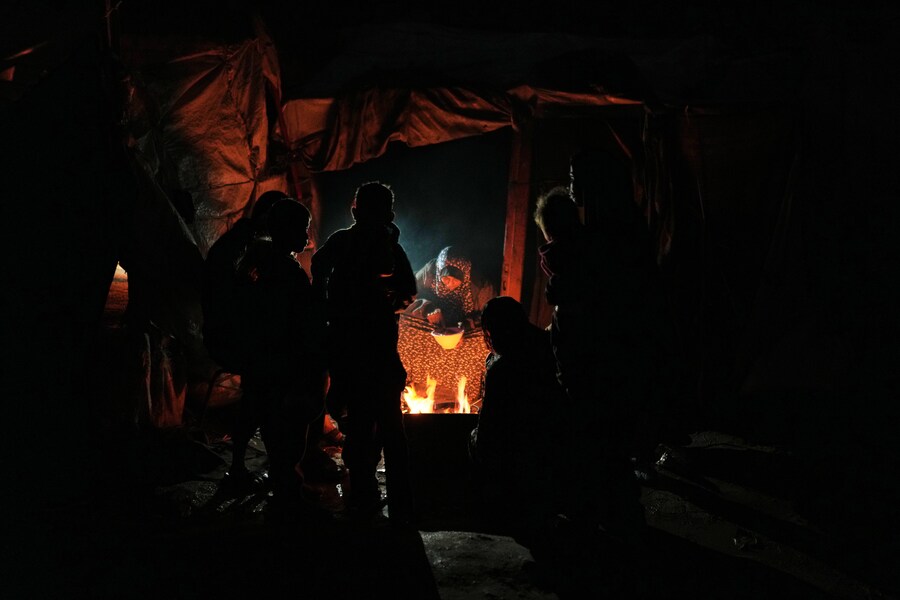 I palestinesi sfollati cucinano e si riscaldano attorno a un fuoco in un campo tendato nella città di Gaza. (APN)