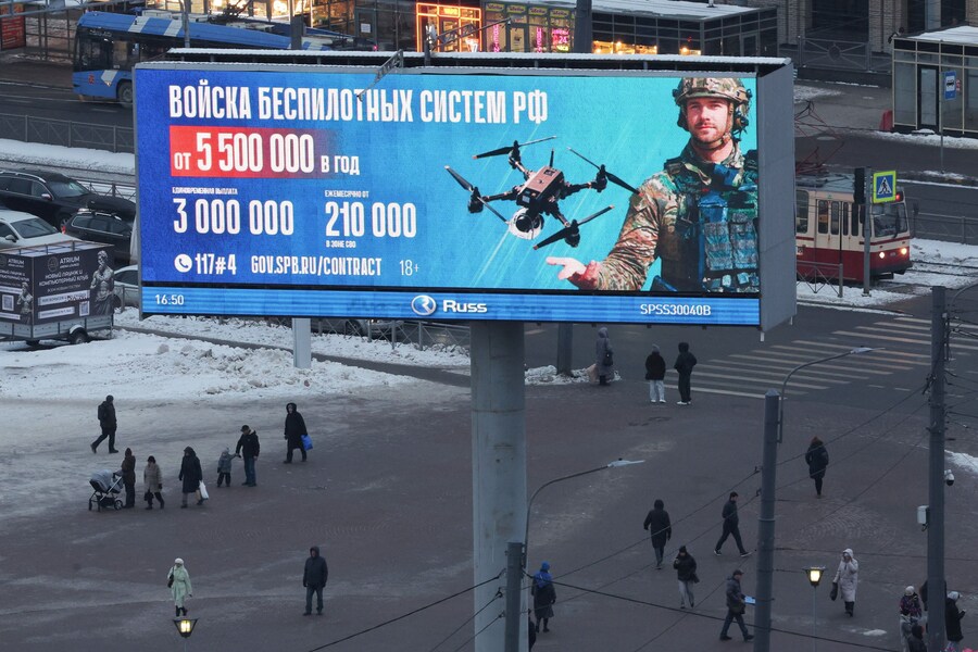 Persone camminano sotto uno schermo digitale che mostra un annuncio pubblicitario che promuove il servizio militare a contratto nelle forze dei sistemi senza pilota dell'esercito russo, con dettagli sul pagamento e informazioni di contatto, a San Pietroburgo, Russia, 26 gennaio 2026. REUTERS/Anton Vaganov (REUTERS)