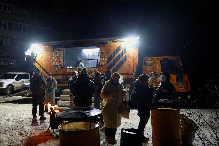 I residenti gustano bevande calde fornite dai veterani della 3ª Brigata d'assalto delle forze armate ucraine dal loro food truck durante un'interruzione di corrente causata dai recenti attacchi missilistici e con droni russi che hanno colpito infrastrutture civili critiche, nel contesto dell'attacco della Russia all'Ucraina, a Kiev, Ucraina, 26 gennaio 2026. REUTERS/Valentyn Ogirenko (REUTERS)