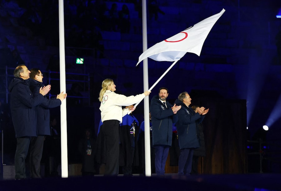 La presidente del CIO Kirsty Coventry sventola la bandiera olimpica durante la cerimonia di consegna delle bandiere, sotto lo sguardo del presidente della regione Provenza-Alpi-Costa Azzurra Renaud Muselier, del presidente della regione Alvernia-Rodano-Alpi Fabrice Pannekoucke, del sindaco di Milano Giuseppe Sala e del sindaco di Cortina d'Ampezzo Gianluca Lorenzi. (REUTERS/Guglielmo Mangiapane)