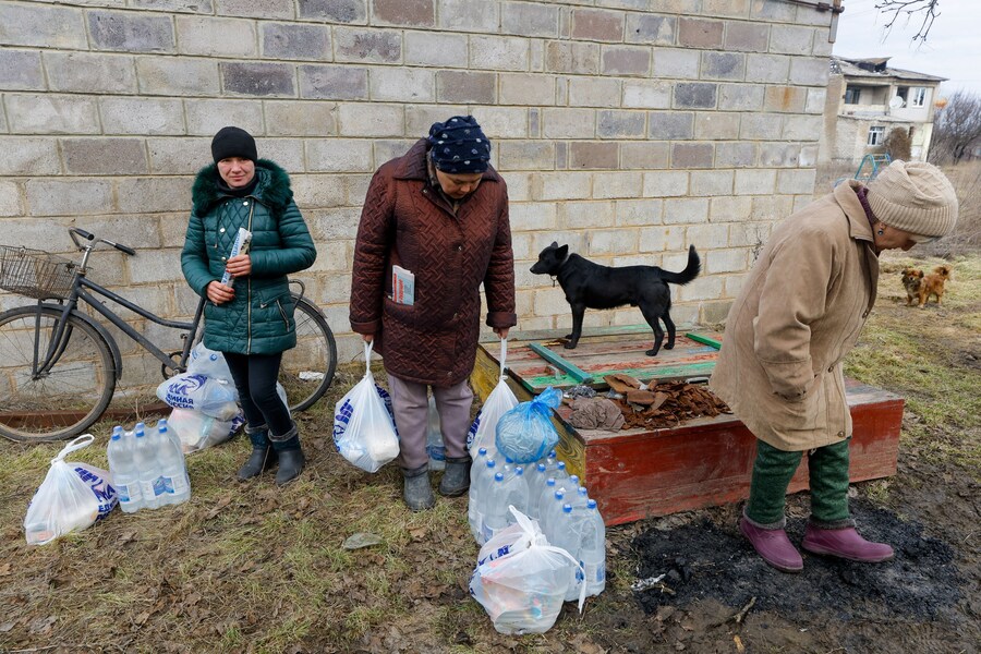 I residenti locali stanno in piedi vicino a bottiglie d'acqua e sacchetti di plastica con generi alimentari mentre i volontari arrivano nell'insediamento di Velyka Novosilka (Velikaya Novosyolovka) per distribuire aiuti umanitari nel mezzo del conflitto militare tra Russia e Ucraina nella regione di Donetsk, un'area dell'Ucraina controllata dalla Russia. REUTERS/Alexander Ermochenko (REUTERS)