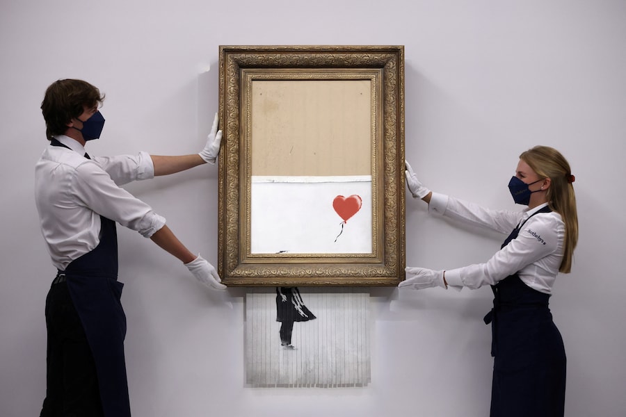 Un assistente della galleria posa accanto a "Love is in the Bin", un'opera di Banksy che sarà messa all'asta da Sotheby's a Londra, in Gran Bretagna, il 3 settembre 2021. REUTERS/Tom Nicholson (REUTERS)