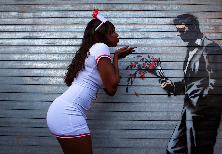 Una ballerina posa accanto a una nuova opera dell'artista di graffiti britannico Banksy, dipinta sulla porta d'ingresso dell'Hustler Club a New York il 24 ottobre 2013. REUTERS/Eric Thayer (REUTERS)