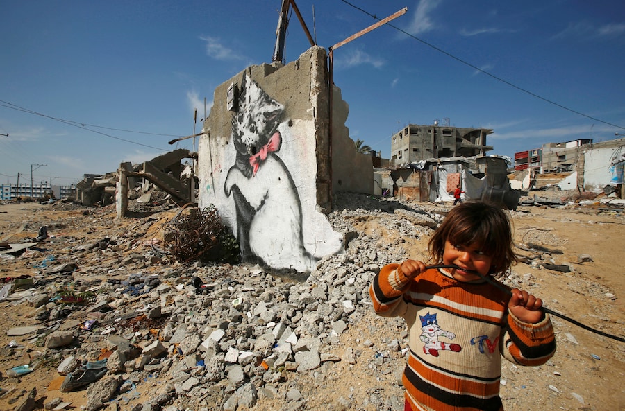 Una bambina palestinese osserva un murale raffigurante un gattino dall'aria giocosa, presumibilmente realizzato dall'artista di strada britannico Banksy, sui resti di una casa che, secondo alcuni testimoni, è stata distrutta dai bombardamenti israeliani durante la guerra dei 50 giorni dell'estate precedente, nella città di Biet Hanoun, nella Striscia di Gaza settentrionale, il 26 febbraio 2015. REUTERS/Suhaib Salem (REUTERS)