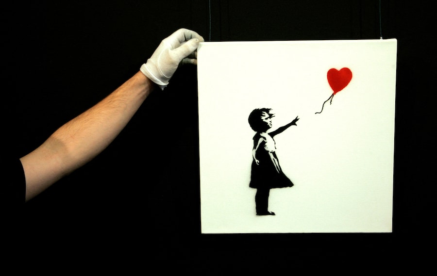 Un tecnico della galleria sistema l'opera di Banksy "Balloon Girl" presso la casa d'aste Sotheby's all'Olympia di Londra, il 2 febbraio 2007. REUTERS / Luke MacGregor (REUTERS)