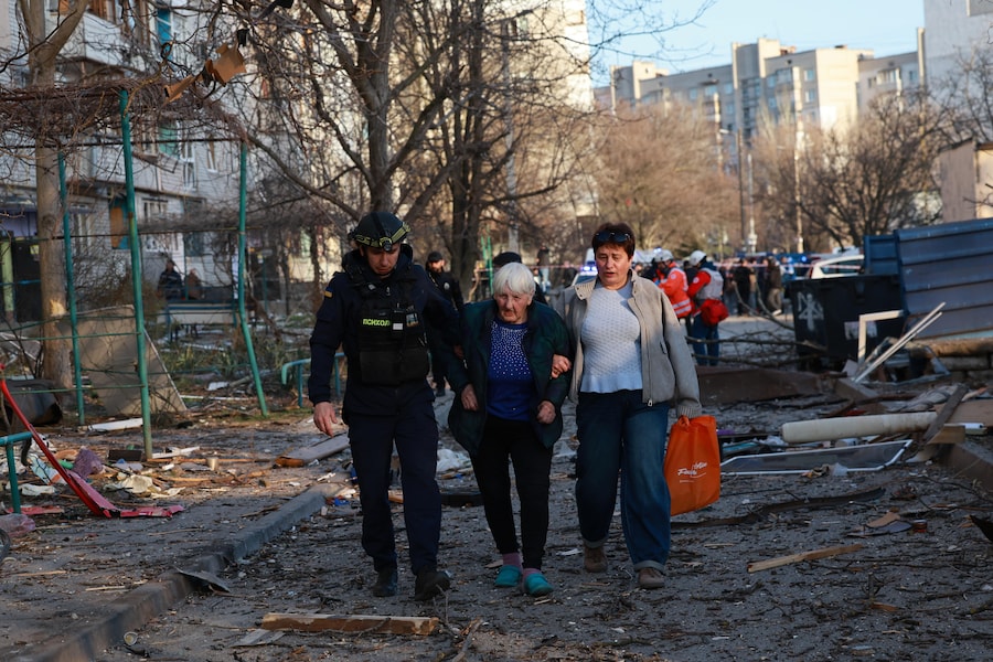 Un soccorritore aiuta un'anziana a uscire dalla sua casa danneggiata da una bomba guidata lanciata dall'aviazione russa a Zaporizhzhia. (AP/Kateryna Klochko/APN)
