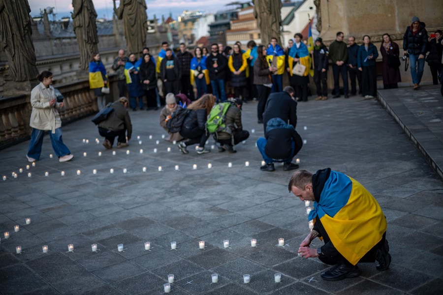 Alcune persone accendono candele durante una manifestazione commemorativa per il quarto anniversario del bombardamento del Teatro Drammatico di Mariupol, sulla terrazza del Teatro Nazionale di Praga, Repubblica Ceca, il 16 marzo 2026. Il Teatro di Mariupol, che fungeva da rifugio per i civili, è stato bombardato il 16 marzo 2022 dalle forze russe nonostante l'avvertimento a grandi lettere "BAMBINI" dipinto all'esterno. Nella commemorazione odierna, questo simbolo è stato ricreato con candele accese, a solenne ricordo delle vite perse durante l'assedio della città portuale ucraina. EPA/MARTIN DIVISEK (EPA)