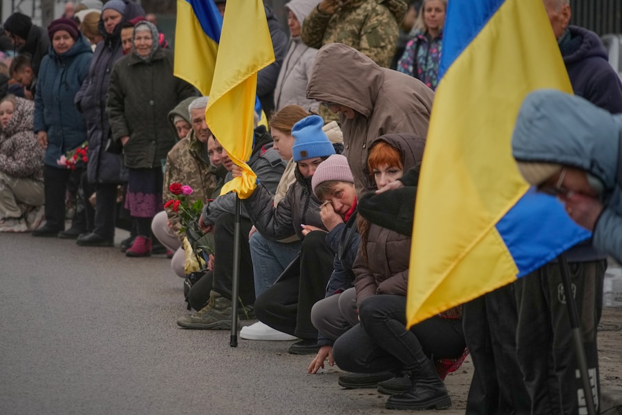Gli abitanti del villaggio si inginocchiano durante il corteo funebre in onore del soldato volontario ventenne Dmytro Dukhota, caduto in battaglia contro le truppe russe, nel villaggio di Novi Petrivtsi, vicino alla capitale Kiev, in Ucraina, mercoledì 18 marzo 2026. (APN)
