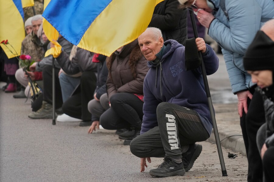 Gli abitanti del villaggio si inginocchiano durante il corteo funebre in onore del soldato volontario ventenne Dmytro Dukhota, caduto in battaglia contro le truppe russe, nel villaggio di Novi Petrivtsi, vicino alla capitale Kiev, in Ucraina, mercoledì 18 marzo 2026. (APN)