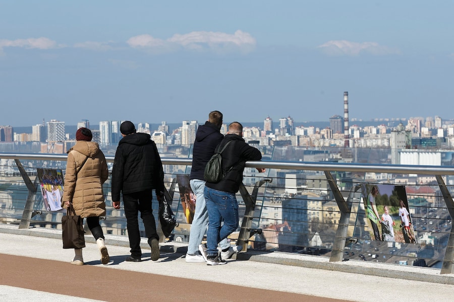 Passanti ammirano il panorama della città dal Glass Bridge mentre passeggiano nel centro di Kiev, in Ucraina, il 20 marzo 2026. (EPA)