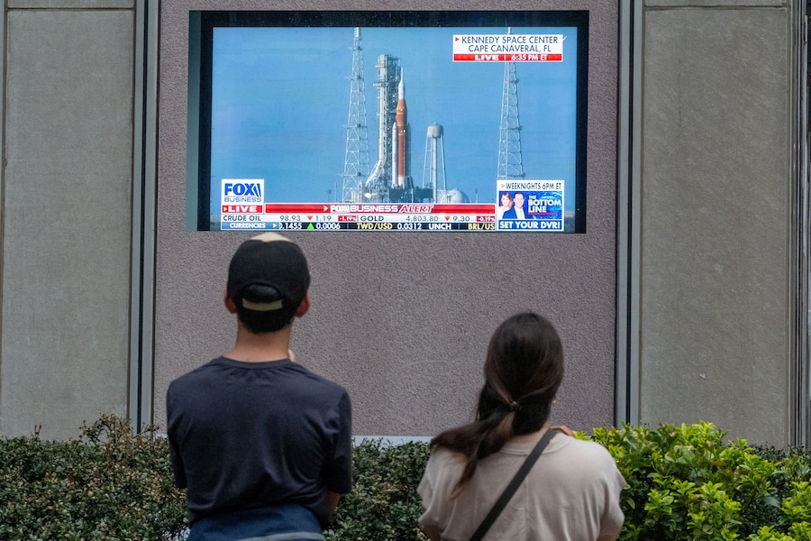 Persone assistono al lancio della missione Artemis II della NASA, destinata al sorvolo della Luna, su un maxi-schermo presso la News Corp. Plaza a Manhattan, a New York (REUTERS)