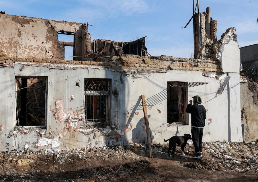 Un residente con il suo cane si trova sul luogo in cui un edificio è stato colpito da un attacco di un drone russo a Odessa, Ucraina (REUTERS)