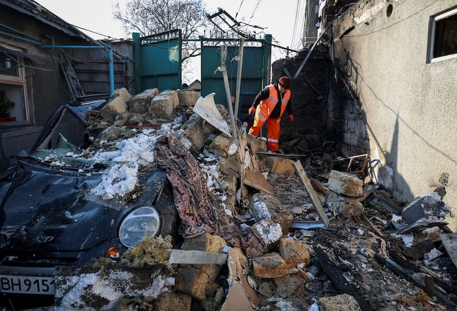 Un’operatrice sanitaria cammina accanto a un’auto gravemente danneggiata mentre ispeziona un edificio colpito da un attacco di un drone russo a Odessa, Ucraina (REUTERS)