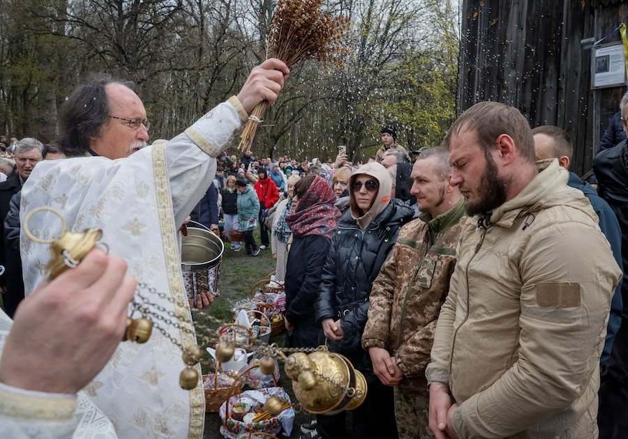 Un sacerdote impartisce la benedizione spruzzando acqua santa durante una funzione pasquale ortodossa, a seguito di una tregua di 32 ore dichiarata dalla Russia, nel contesto dell'attacco russo all'Ucraina, nei pressi della chiesa del Museo Nazionale di Architettura Popolare a Kiev, Ucraina, il 12 aprile 2026. REUTERS/Gleb Garanich (REUTERS)