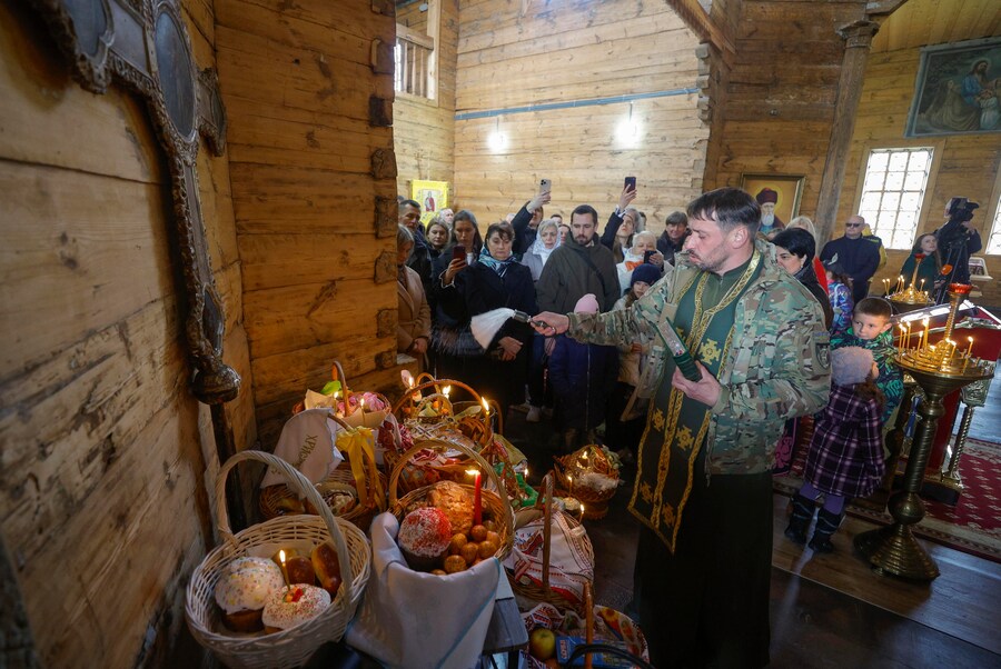 I sacerdoti ucraini benedicono i fedeli e i loro cestini contenenti uova dipinte e kulichi, un dolce tradizionale pasquale, nella chiesa di San Nicola presso il Museo di Architettura Popolare ed Etnografia nel villaggio di Pyrohovo, nei pressi di Kiev, Ucraina, il 12 aprile 2026, mentre i cristiani ortodossi ucraini celebrano la Pasqua nel contesto dell'invasione russa in corso. EPA/SERGEY DOLZHENKO (EPA)
