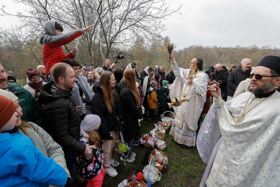 Alcuni sacerdoti ucraini benedicono i fedeli e i loro cestini contenenti uova dipinte e kulichi, un dolce pasquale tradizionale, nei pressi della chiesa dell’Arcangelo San Michele nel Museo di Architettura Popolare ed Etnografia nel villaggio di Pyrohovo, vicino a Kiev, Ucraina, il 12 aprile 2026, mentre i cristiani ortodossi ucraini celebrano la Pasqua nel mezzo dell’invasione russa in corso. EPA/SERGEY DOLZHENKO (EPA)