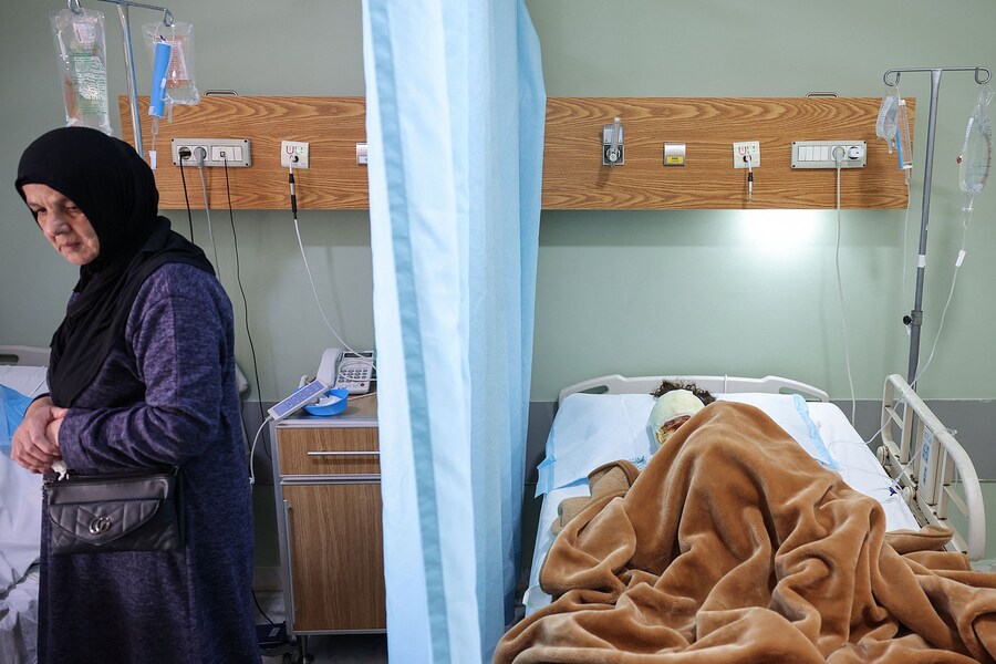 La zia di Aline Saeed, 7 anni, è in piedi accanto al letto della madre di Aline, Ghinwa (non presente nella foto), mentre entrambe ricevono cure per le ferite riportate nel recente attacco israeliano al villaggio di Srifa, che ha causato la morte di quattro membri della famiglia, presso l’ospedale Jabal Amel di Tiro, in Libano, l’11 aprile 2026. REUTERS/Louisa Gouliamaki (REUTERS)