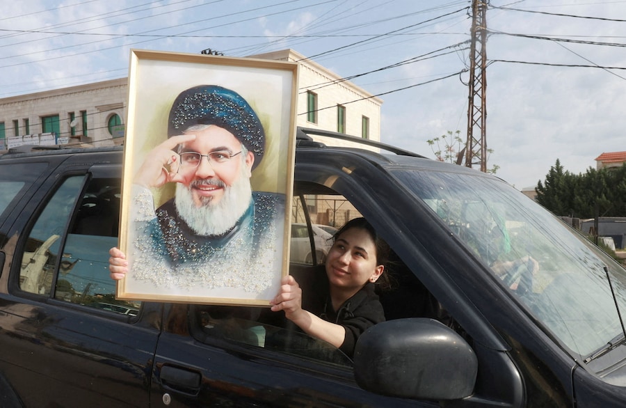 Una donna in auto mostra una foto dell’ex leader di Hezbollah, Hassan Nasrallah, dopo l’entrata in vigore di un cessate il fuoco di 10 giorni tra Libano e Israele, vicino a Nabatieh, in Libano (REUTERS)