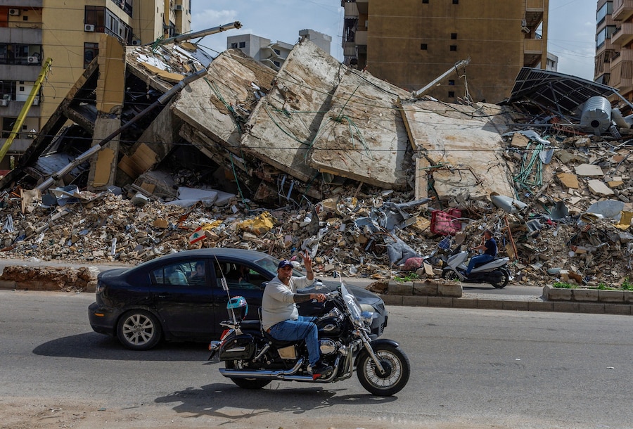 Un uomo fa il segno della vittoria mentre passa in motocicletta davanti a un edificio danneggiato, mentre le persone tornano temporaneamente alle proprie case dopo l’entrata in vigore di un cessate il fuoco di 10 giorni tra Libano e Israele, nella periferia meridionale di Beirut, Libano (REUTERS)