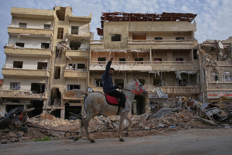 Un uomo cavalca un cavallo passando accanto al sito degli edifici distrutti da un attacco aereo israeliano, a Jibchit, nel Libano meridionale (APN)