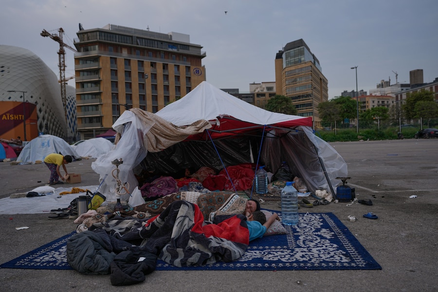 Una donna sfollata con suo figlio dorme fuori dalla loro tenda in attesa di un ordine ufficiale da Hezbollah per tornare a casa nel sud del Libano, dopo il cessate il fuoco tra Hezbollah e Israele a Beirut, Libano (APN)