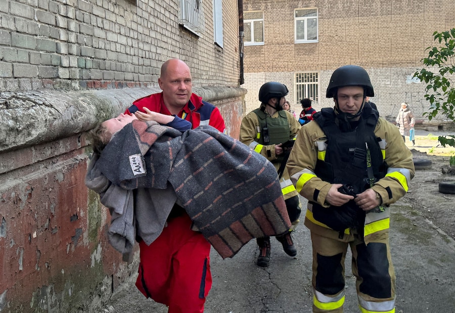 Un operatore sanitario trasporta un bambino sul luogo dell’attacco a un condominio colpito da un drone russo, durante l’offensiva russa contro l’Ucraina, a Zaporizhzhia, Ucraina (REUTERS)