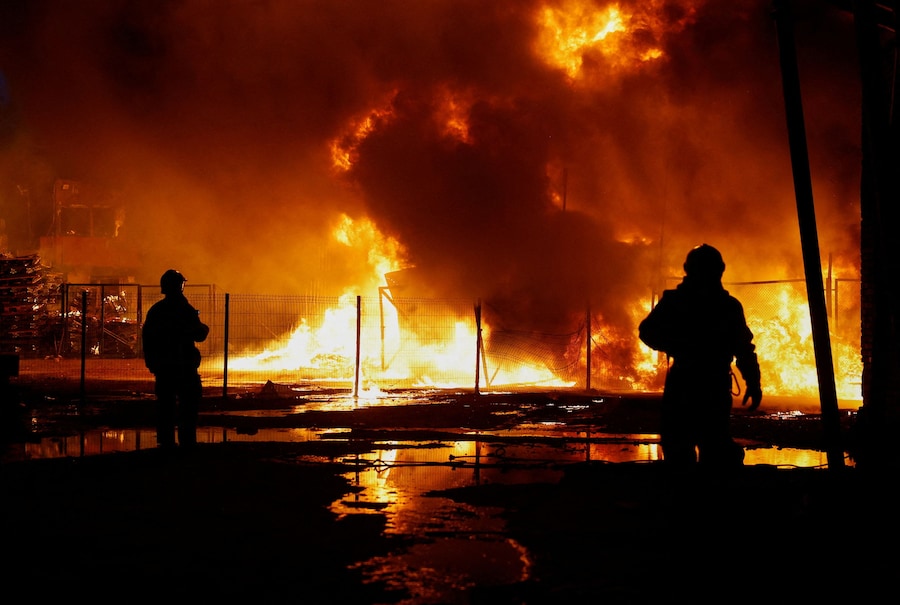 Vigili del fuoco al lavoro sul sito di un deposito di materiali riciclabili colpito da un missile russo a Kiev (REUTERS)