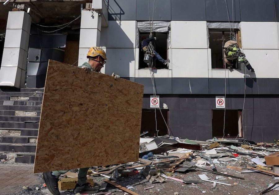 Operai installano pannelli OSB al posto delle finestre rotte di un hotel colpito ieri da un missile e da un attacco con droni russi, nel contesto dell'offensiva russa contro l'Ucraina, a Kiev. (REUTERS/Anatolii Stepanov)
